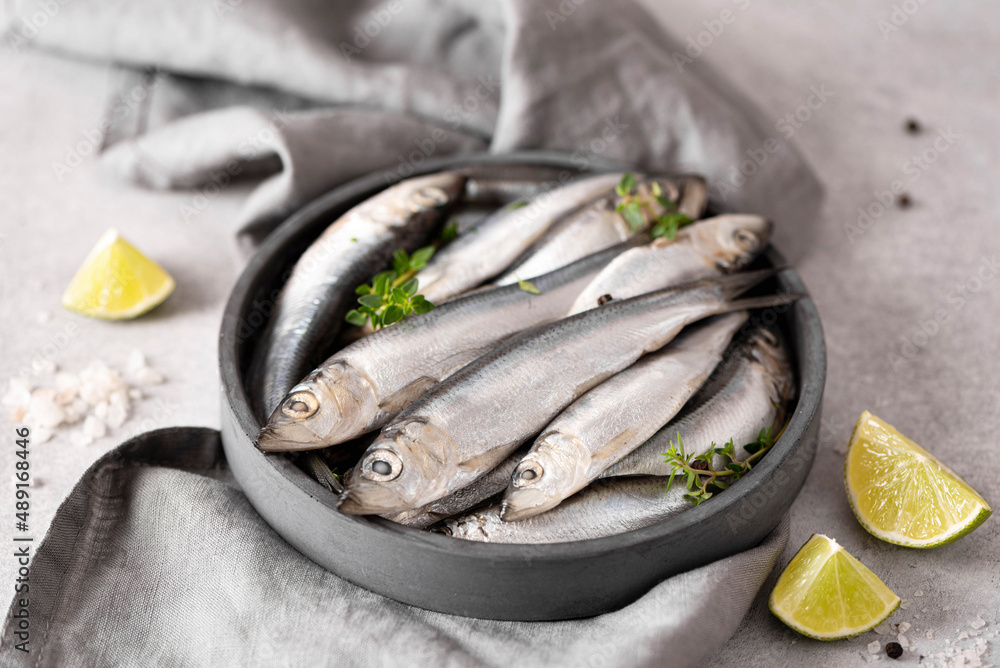 fresh large sardines with lemon, spices and sea salt on a gray plate