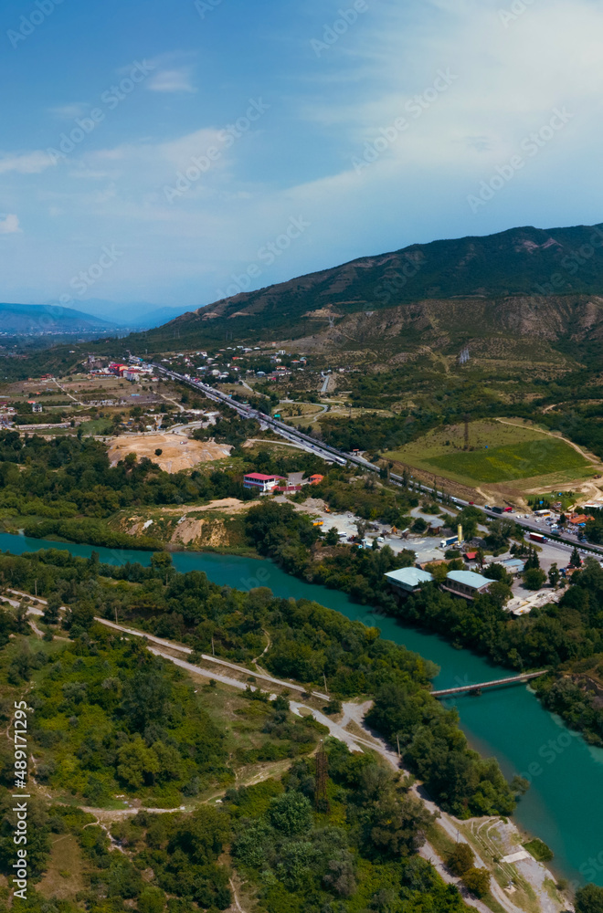 A place where two rivers of different colors meet. Aerial view panorama. Mountains. Travel and vacation concept. Summer day. Tsitsamuri in Georgia. Vertical photo