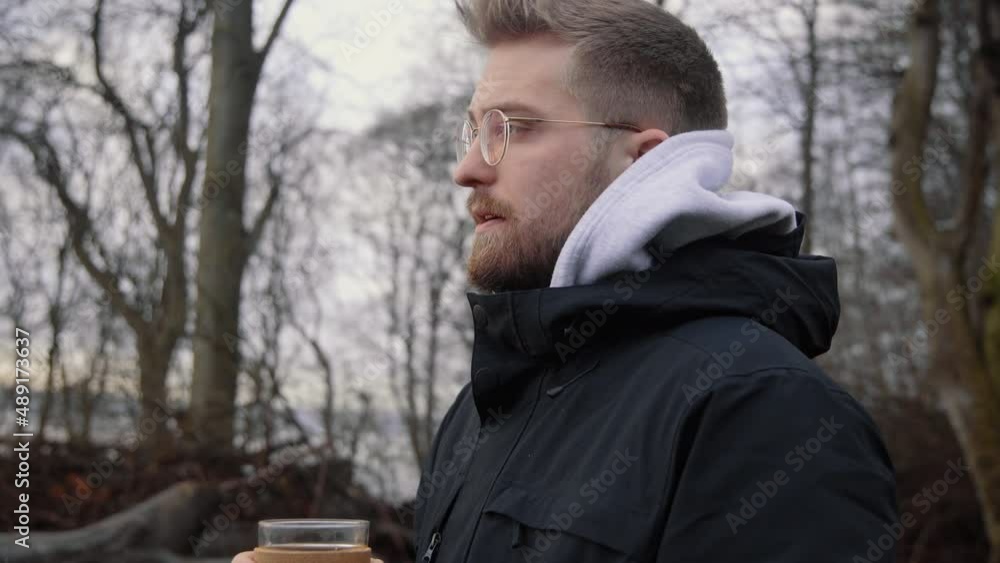 Young caucasian male drinking hot coffee from a sustainable keep cup out of glass. Early in the morning outdoors forest. Young caucasian male drinking hot coffee from a sustainable keep cup out of glass. Early in the morning outdoors forest.