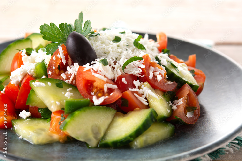 Traditional Bulgarian shopska salad with tomato,cucumber and bulgarian sirene cheese on wooden table Traditional Bulgarian shopska salad with tomato,cucumber and bulgarian sirene cheese on wooden table