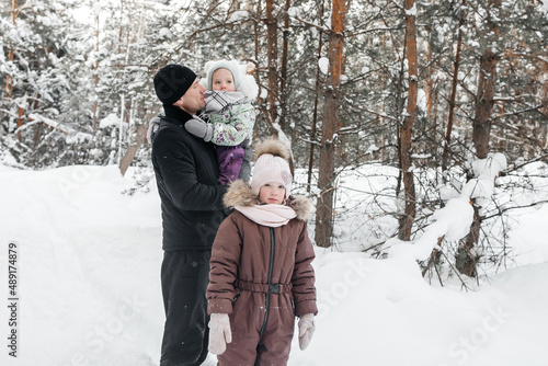 father with two daughters walking through the winter forest © Svetlana Repnitskaya