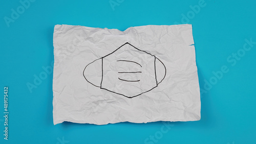 medical mask mark drawn on crumpled paper. Mask protective coronavirus isolated on blue background with copy space. Health care medical hygiene concept. © Misha