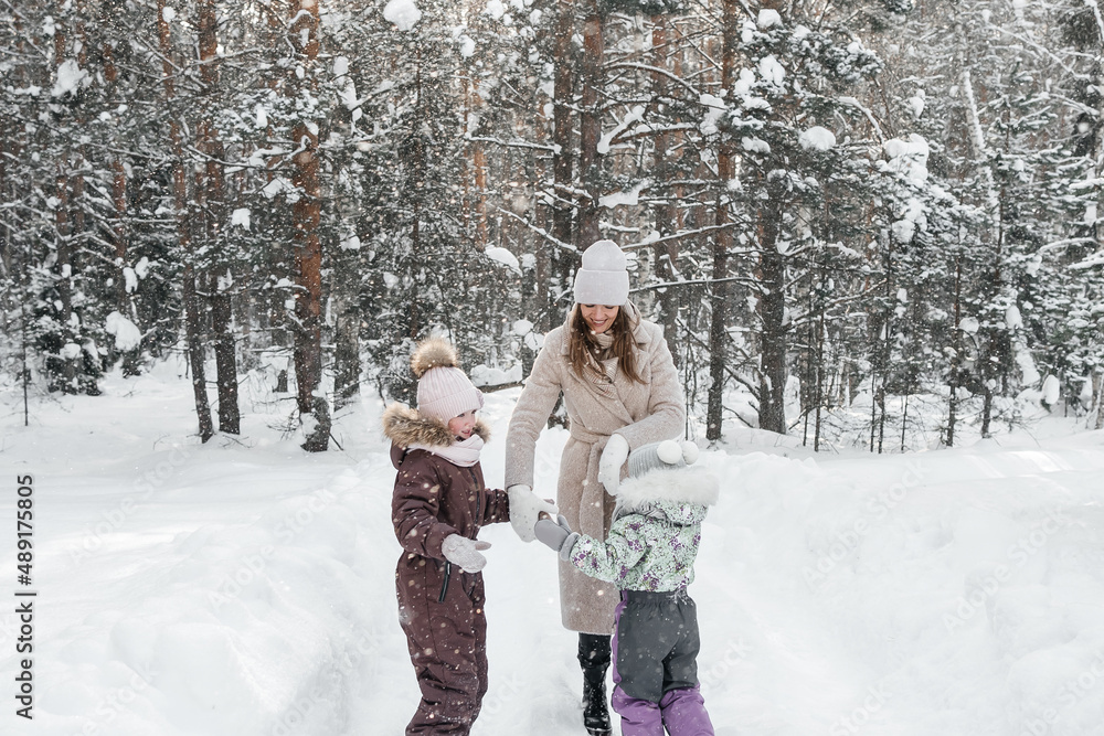 mother with two daughters walks in a snowy forest on her day off mother with two daughters walks in a snowy forest on her day off