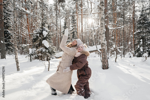 mother and daughter playing in the winter sunny forest
