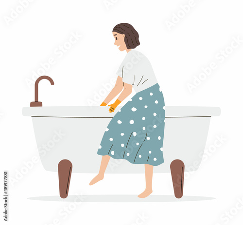 Woman washing the bathtub in rubber gloves