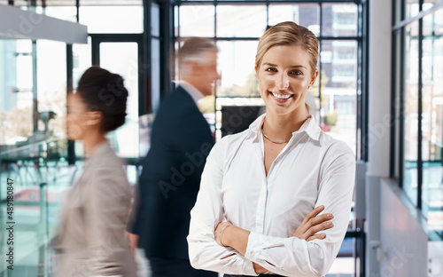 Our offices are always a hive of activity. Portrait of a young businesswoman standing in a busy office.