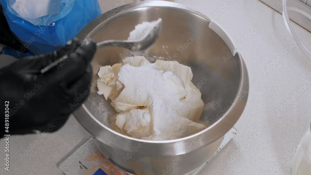 Confectioner kneads cream cheese with powdered sugar Confectioner kneads cream cheese with powdered sugar