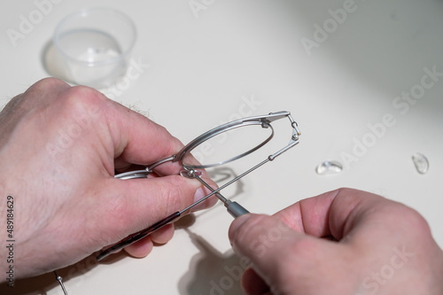 Installation of nose pads in glasses. A male technician repairs broken glasses