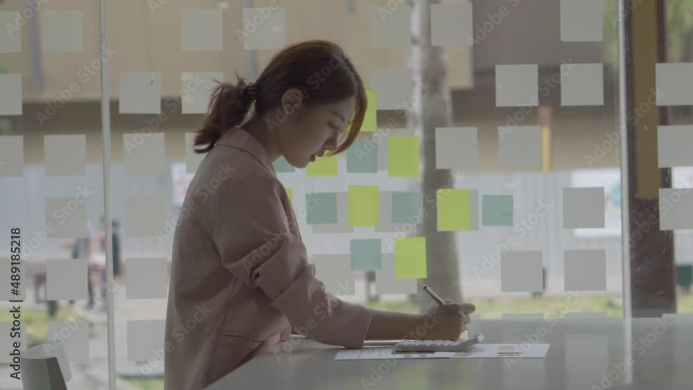 Young accountant analyzing calculating financial accounts with graphs with calculator Young accountant analyzing calculating financial accounts with graphs with calculator