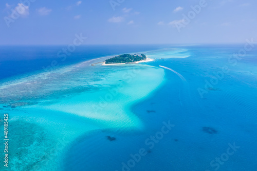 Atoll island with white sand beach, turquoise transparent water, coral reef, blue sky. Perfect tropical vacation holidays destination in Maldives. Aerial view from seaplane.