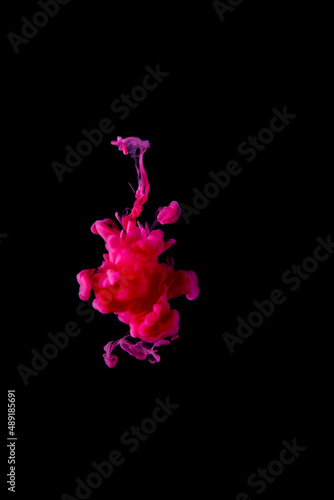 Red acrylic ink is scattered in the water, creating strange shapes. on a black background abstract background