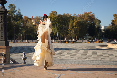 Young flamenco woman, Hispanic and brunette, with typical flamenco dance suit, with bullfighter jacket, dancing lifting her skirt. Concept of flamenco, dancer, typical Spanish dance.