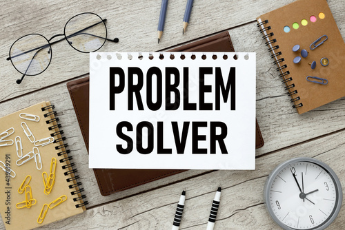 Fotografi PROBLEM SOLVER,brown notebook with a white sheet of paper with text on the table, next to a pen and glasses