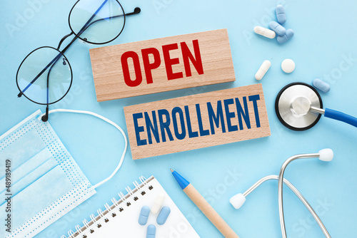OPEN ENROLLMENT . text on wooden blocks on a blue background. stethoscope pills medical mask. medicine concept