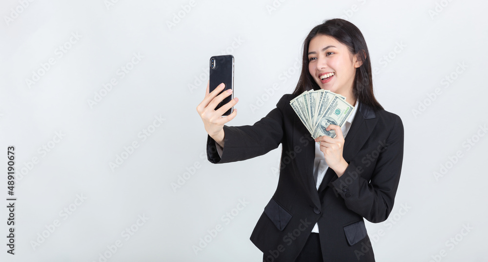 business asian woman wearing office clothing successful hold smart phone mobile and US dollars money in hand feeling happy and smile, bankruptcy economic financial concept. business asian woman wearing office clothing successful hold smart phone mobile and US dollars money in hand feeling happy and smile, bankruptcy economic financial concept.