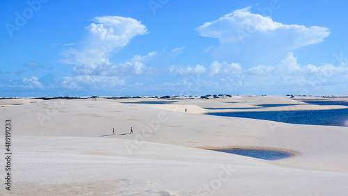 People are enjoying their free time walking in the dunes and lagunes of national park Lencois Maranhenses in Brazil photo