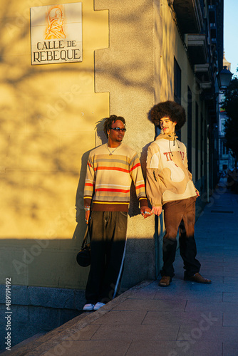Gay couple holding hands in the sun.