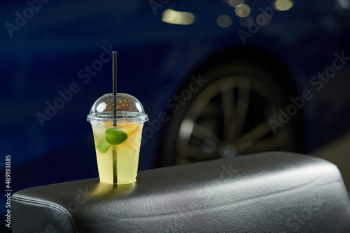 Лимонад с мятой в стакане с трубочкой на фоне автомобиля