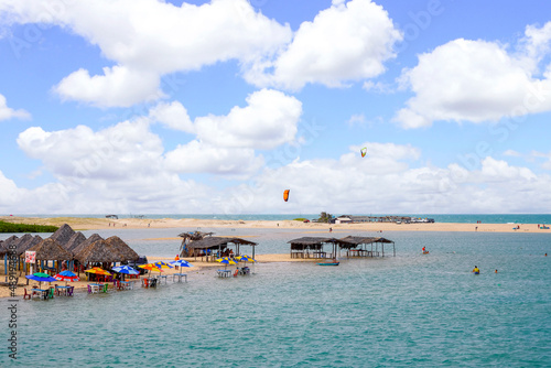 Beach bar and Kitesurfer on a lagoon with dunes in Brazil