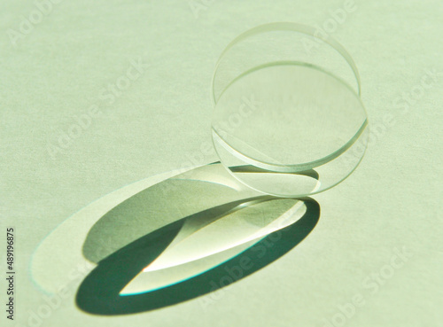 Close up of sunlight through clear circular convex and concave lens with different focus lengths overlapping. Mixture refection and refraction of light create artistic shade and shadow on white paper photo