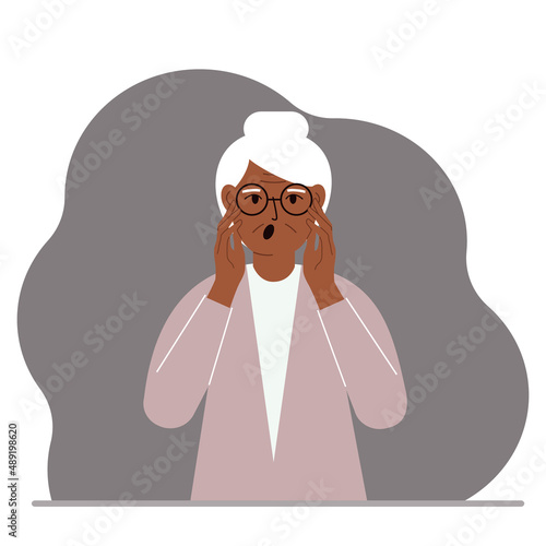 The unhappy grandmother screams, clutching his head with his hands. Emotions and body language concept. Stress, tension and migraine concept.