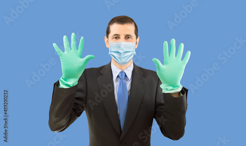 Happy businessman with face mask and gloves ready to do homework on blue background.