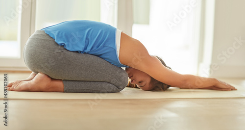 Staying relaxed with yoga. Shot of a young woman doing yoga at home.