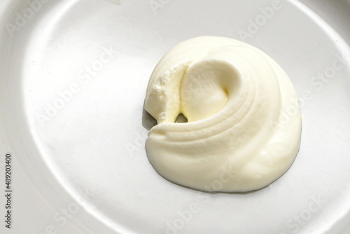 Sour cream sauce on a white plate close-up