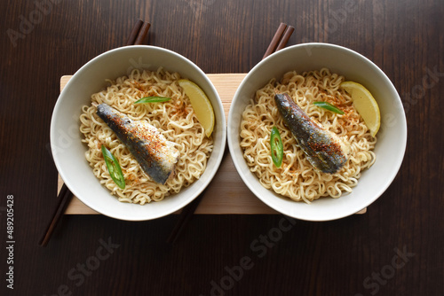Instant noodles with sardine, chillies and seasonings in ceramic bowls. Flat lay top view photo. Food from above.
