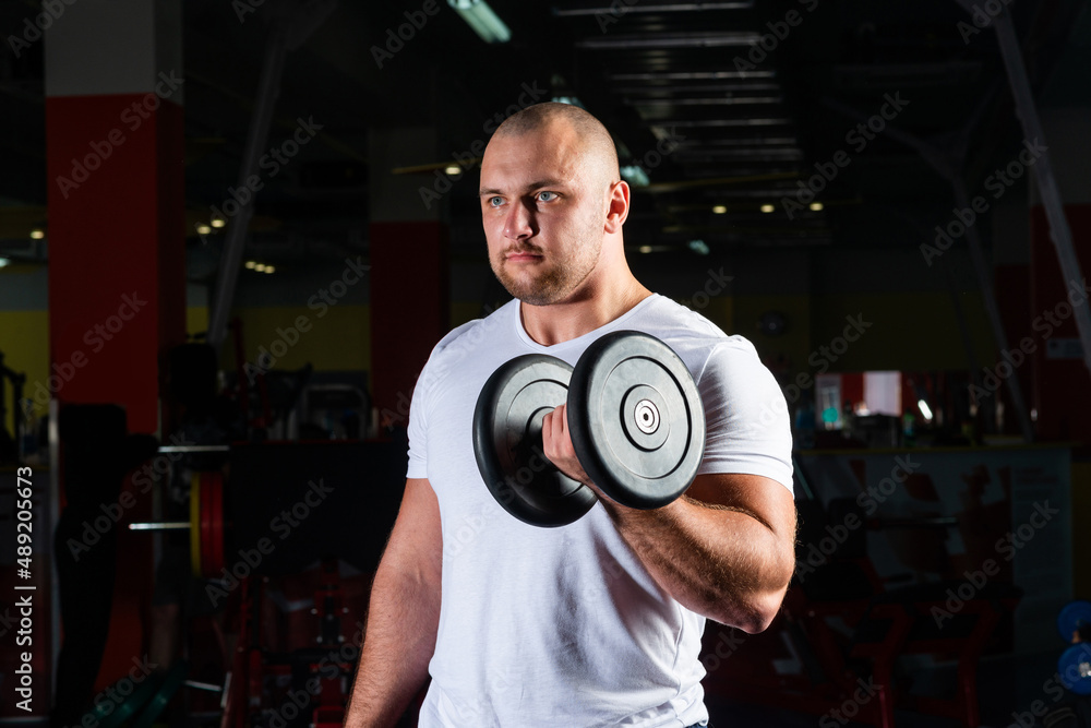Male bodybuilder engaged with dumbbells in the gym