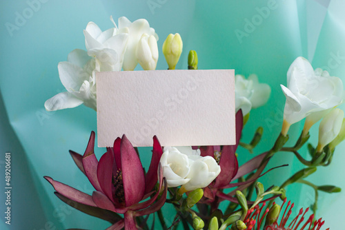 card mockup with exotic bouquet of flowers. Leukadendron red and leukospermum, freesia photo