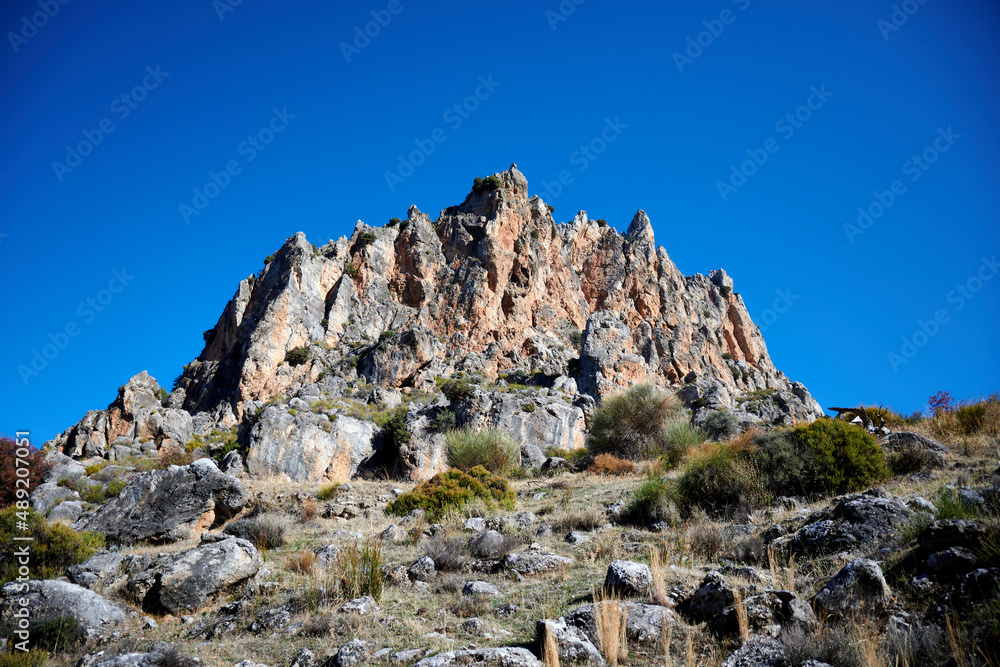A view of rocky mountains with a clear blue sky on the background in Granada, Spain