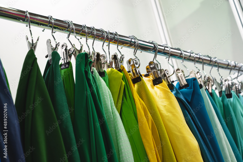 Samples of green yellow and blue fabrics hang on rack bar Samples of green yellow and blue fabrics hang on rack bar