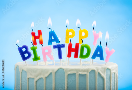 Blue Birthday Cake with Happy Birthday candles on Top on a Blue Background