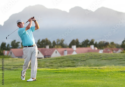 Perfect form and follow through. A male golfer admiring the shot he has just played.