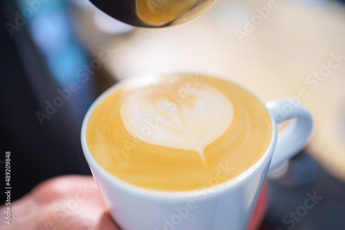 barista pouring milk into espresso coffee for making cappuccino, latte art