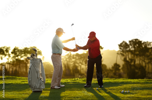 Keep the club level right through your swing. A male golfer receiving help from his caddy on the golf course.