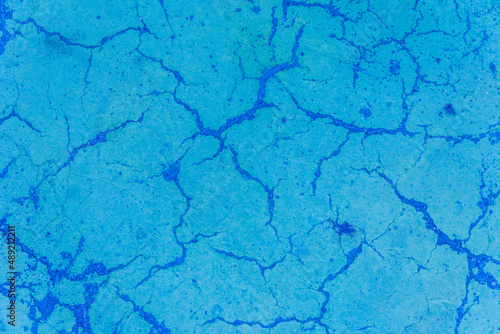 Cracks on blue paint concrete surface cracked weathered cement worn texture broken abstract damaged pattern background © Andrey