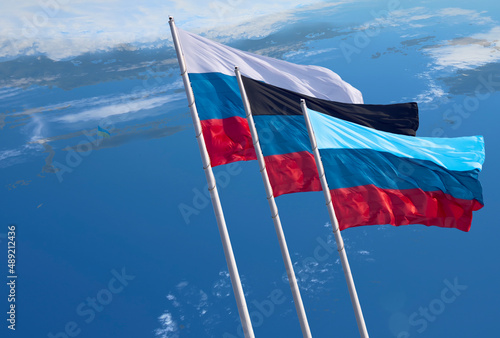 Flags of Russia and the partially recognized republics of Donetsk and Lugansk oblasts  on a blue background. Close-up of banners fluttering in the wind. photo
