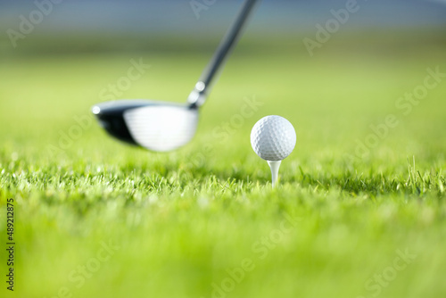 The first drive is vital. A golf club about to tee-off with a white ball on a golf course.