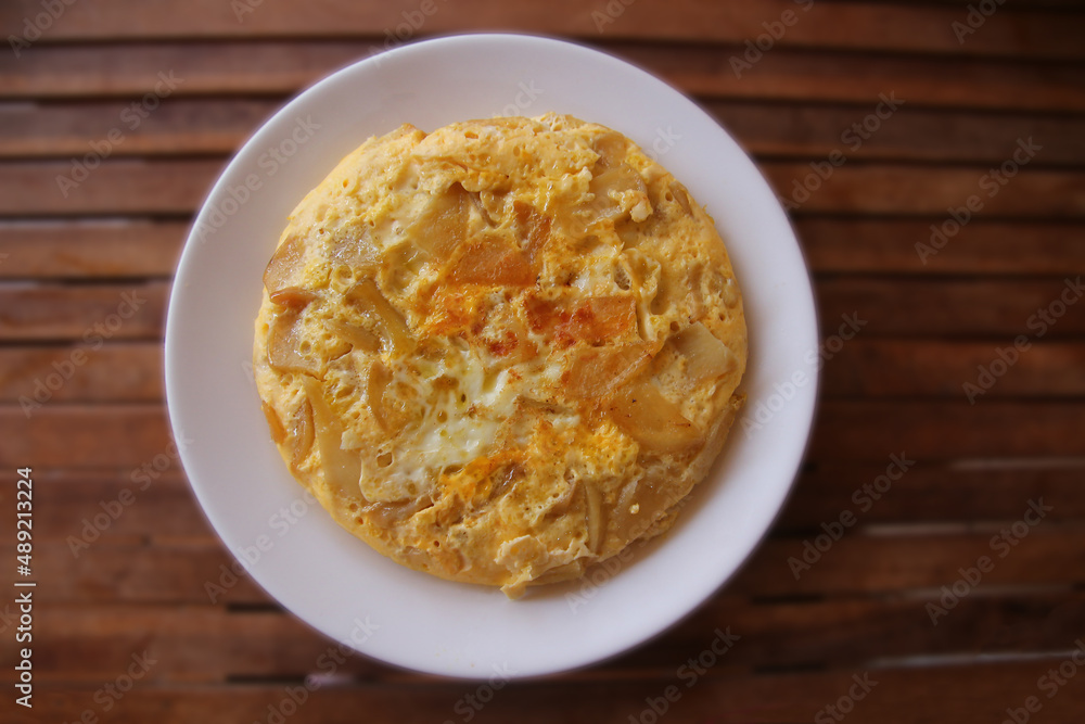 White plate with home-made Tortilla espanola (Spanish omelette) - a Spanish traditional dish on wooden table in bokeh White plate with home-made Tortilla espanola (Spanish omelette) - a Spanish traditional dish on wooden table in bokeh