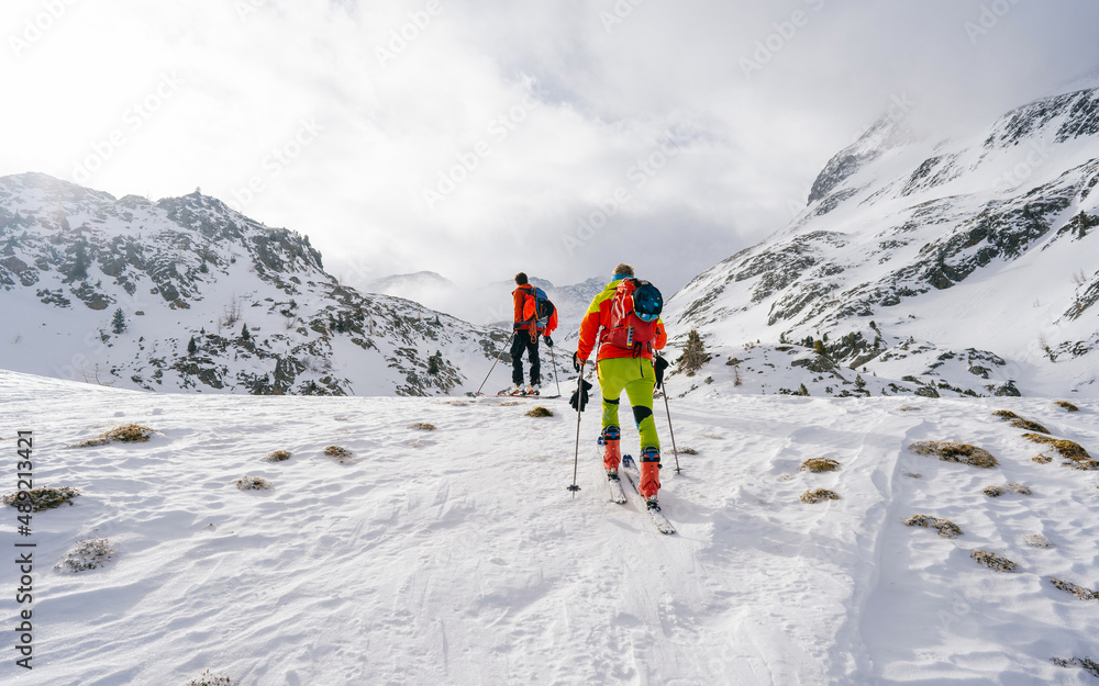 Ski touring couple hiking up a summit in the alps. Concepts: adventure, achievement, courage, determination, extreme sport