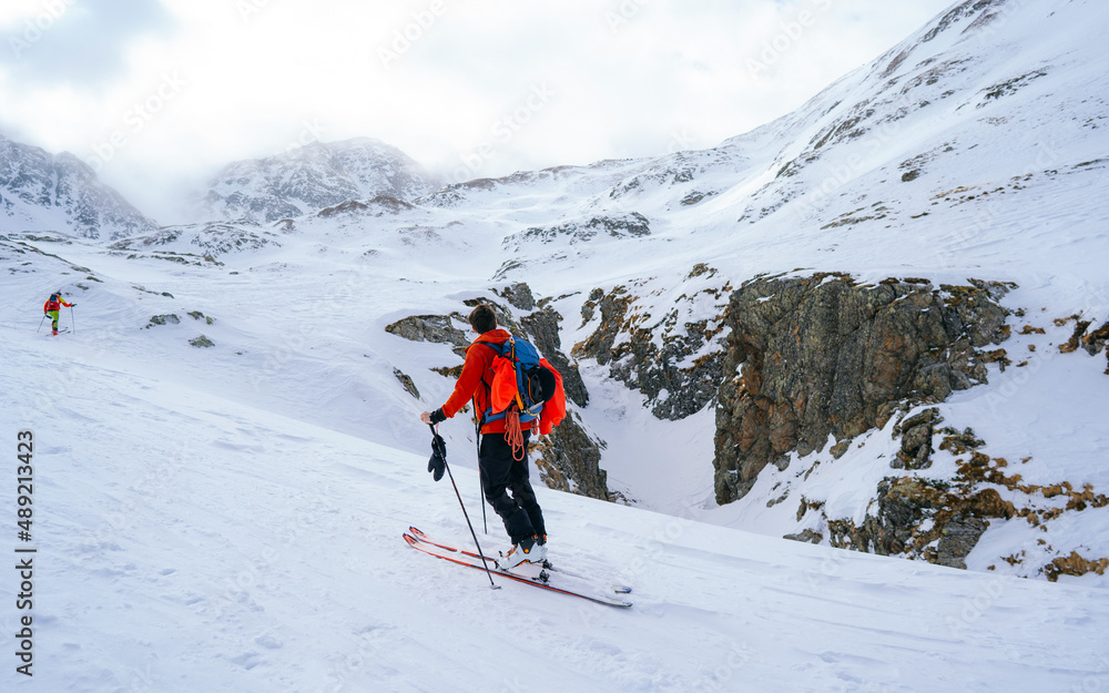 Portrait of a young male athlete skier in a ski tour on skis on the background of snow-capped mountains on a sunny day. Skitour professional