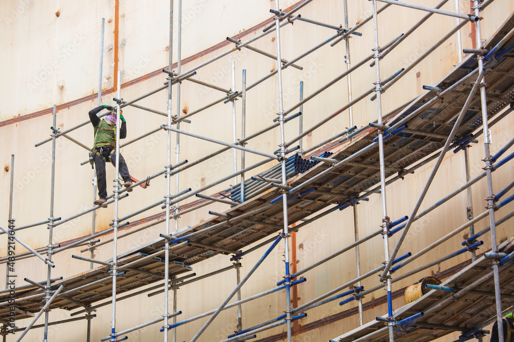 Worker male assembly in progress storage tank oil inspection scaffolding work at high Worker male assembly in progress storage tank oil inspection scaffolding work at high