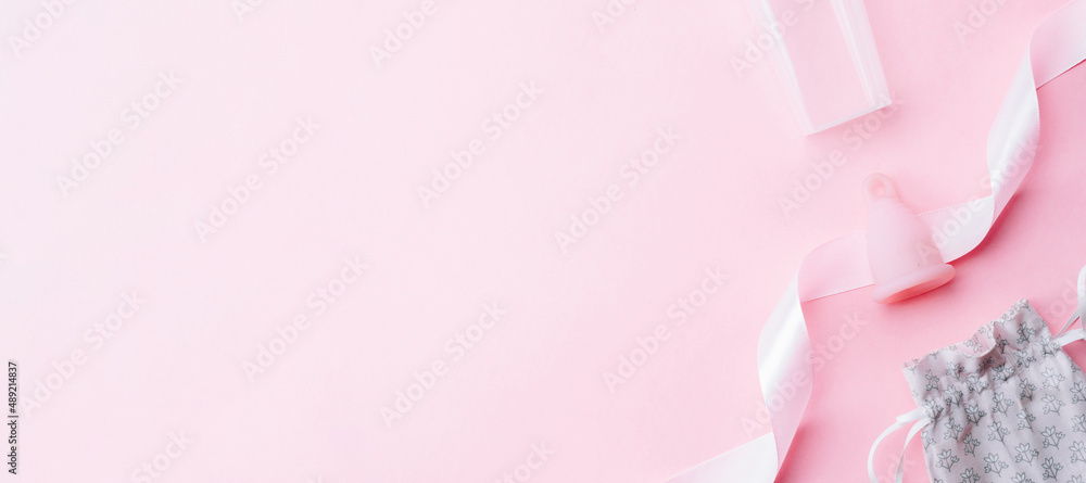 Menstrual period use cup. Pink ribbon with menstrual cup. Menstruation feminine period. Women health concept. Zero waste banner. Top view. Menstrual period use cup. Pink ribbon with menstrual cup. Menstruation feminine period. Women health concept. Zero waste banner. Top view.