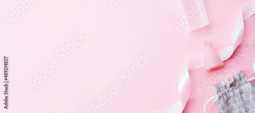 Menstrual period use cup. Pink ribbon with menstrual cup. Menstruation feminine period. Women health concept. Zero waste banner. Top view. © Maksym