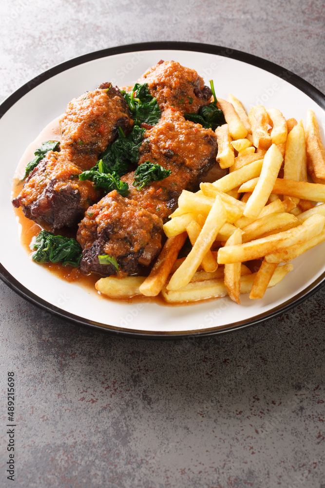 Rabo De Toro delicious dish in Spain is oxtail stew served with french fry closeup in the plate on the table. Vertical Rabo De Toro delicious dish in Spain is oxtail stew served with french fry closeup in the plate on the table. Vertical