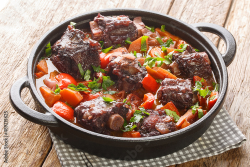 Traditional spanish dish slow cooked oxtail in red wine sauce with rabo de toro closeup on a pot on the wooden table. Horizontal