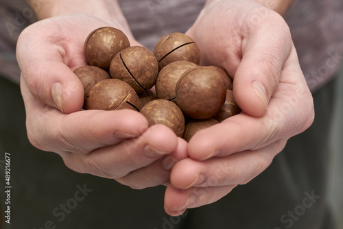 a man holds a handful of macadamia nuts in his palms close-up