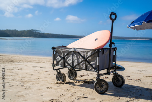 Outdoor beach cart wagon and beach umbrella on a sandy beach near the ocean. Family vacation holidays